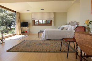 habitación de hotel parquet de bambú vertical caramel amueblada con cama de matrimonio, silla y alfombra grande