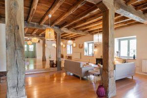 caserío en navarra con vigas en madera vistas y suelo en parquet de bambú. sala de estar con un par de sillones a la derecha de la imagen